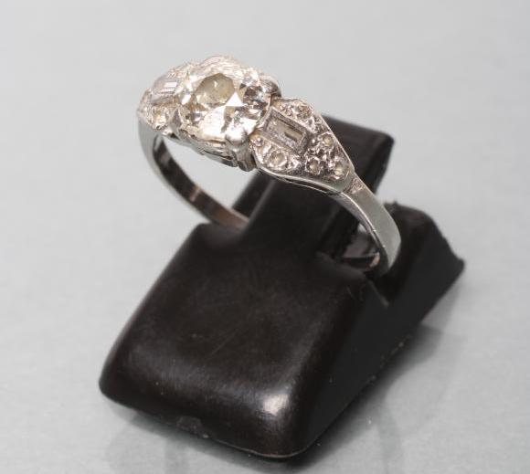 AN ART DECO DIAMOND RING, the brilliant cut centre stone claw set to shaped triangular shoulders