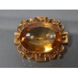 A VICTORIAN CITRINE BROOCH, the oval facet cut stone centred by two peg set small pearls, in a