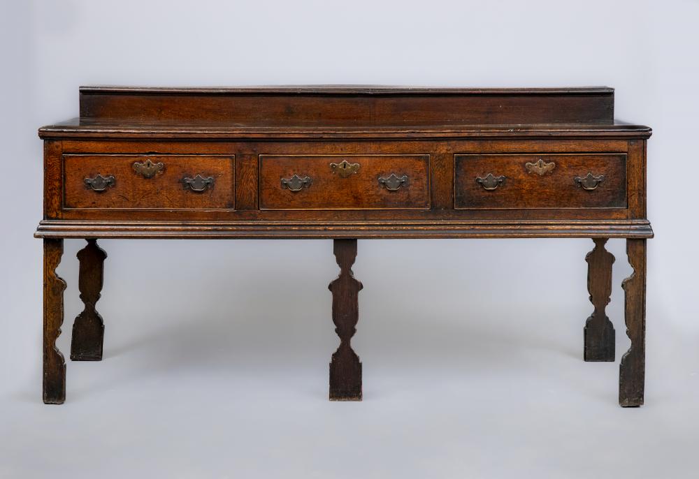 A GEORGIAN OAK LOW DRESSER, mid 18th century, the moulded edged top with raised plate stand, three