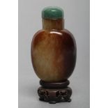 A CHINESE POLISHED OLIVE GREEN JADEITE SNUFF BOTTLE with amber/brown mottling, 2 1/4" high, with