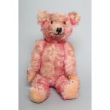 A pre-war pink musical jointed teddy bear, with wind-up mechanism, pink plush, amber eyes, sewn nose