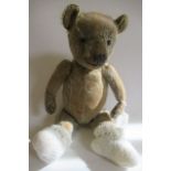 A pre-war jointed teddy bear, straw filled with glass eyes, sewn nose and cloth pads, 16" long (Est.