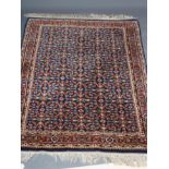 A PERSIAN RUG, the navy blue field with repeating pattern of foliate scrolls and flower heads, the