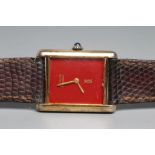 A MUST DE CARTIER SILVER GILT WRISTWATCH, the dark red oblong dial with gilt metal hour and minute