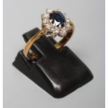 A SAPPHIRE AND DIAMOND CLUSTER RING, the oval facet cut sapphire claw set to a border of ten small