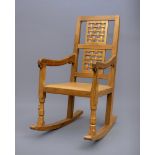 A ROBERT THOMPSON OAK ROCKING CHAIR, the tapering back with straight top rail over a pierced