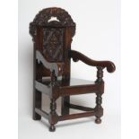 A CHILDS JOINED OAK ARMCHAIR, in 17th style, the panelled back carved with foliage and surmounted by