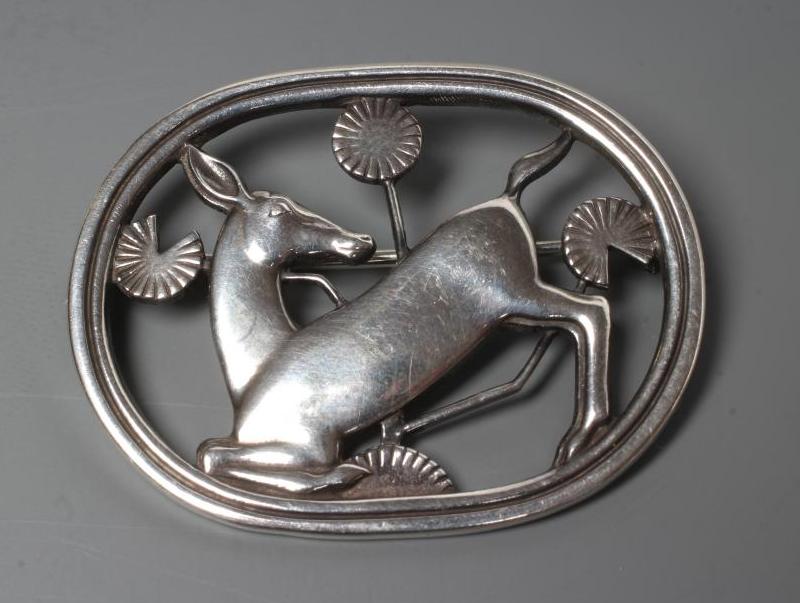 A GEORG JENSEN SILVER OVAL BROOCH designed by Arno Malinowski, cast as a kneeling deer, stamped