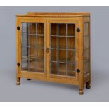 A ROBERT THOMPSON ADZED OAK DISPLAY CABINET of canted oblong form with leaded glazed doors and