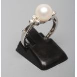 A CULTURED PEARL RING, the white pearl set to shoulders line set with three small diamonds to a