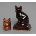 AN ENGLISH TREACLE GLAZED STONEWARE CAT, early 19th century, modelled seated on an oblong base, 7