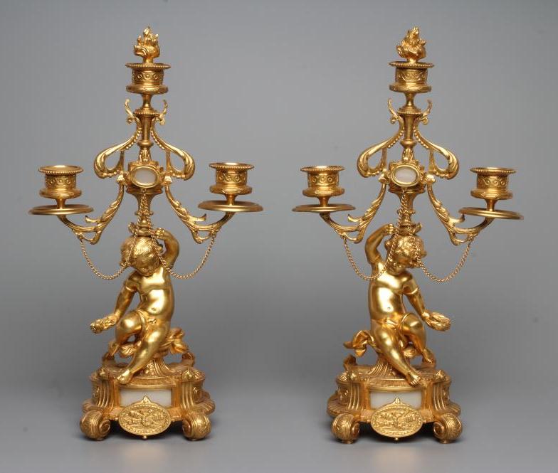 A PAIR OF FRENCH GILT METAL THREE LIGHT FIGURAL CANDELABRA inset with onyx panels, early 20th