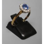 A SAPPHIRE AND DIAMOND CLUSTER RING, the oval facet cut sapphire of approximately 0.44cts claw set