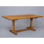 A ROBERT THOMPSON ADZED OAK DINING TABLE, the rounded oblong plank top raised on turned faceted