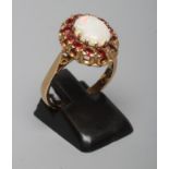 AN OPAL AND GARNET CLUSTER RING, the oval cabochon polished opal claw set to a border of small facet