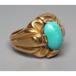 A GENTLEMAN'S RING, the oval cabochon polished turquoise set to an open fancy surround and wide