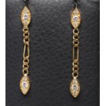 A PAIR OF DIAMOND DROP EAR STUDS, the eliptical panel pave set with three small stones hung with a