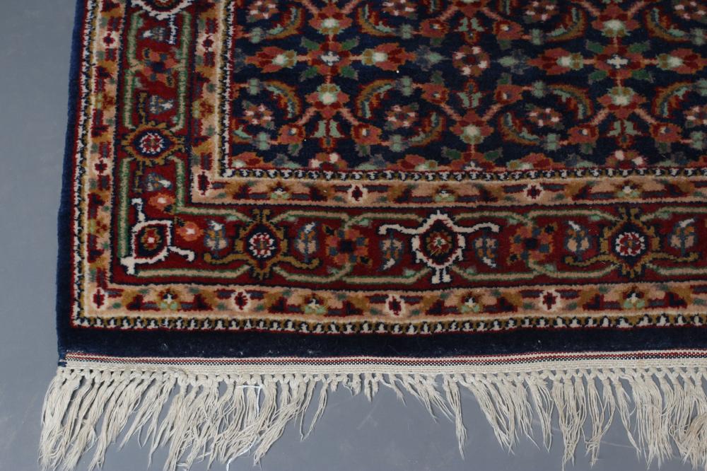 A PERSIAN RUG, the navy blue field with repeating pattern of foliate scrolls and flower heads, the - Image 2 of 3