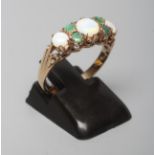 AN OPAL AND EMERALD RING, the three graduated cabochon opals point set with two pairs of small