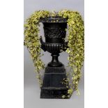 A CAST IRON GARDEN URN of half fluted campana form with lion mask loop handles, the body with a band