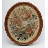 A MID VICTORIAN OVAL WOOLWORK PICTURE worked in coloured wools in full cross stitch with flowers