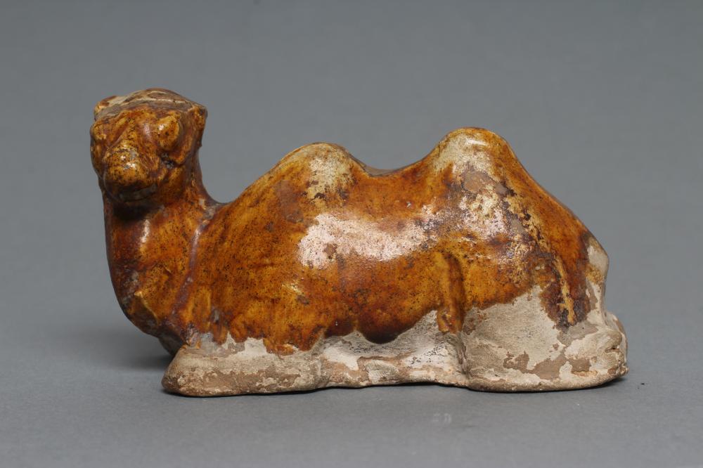 A SMALL TANG STYLE RECUMBENT CAMEL, with museum style/collectors number K61/1706 inscribed in black,