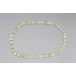A STRING OF CHINESE CELADON JADE BEADS, the forty six spherical beads carved with scroll and