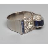 AN ART DECO STYLE SAPPHIRE AND DIAMOND "BUCKLE" COCKTAIL RING, the central diamond of