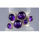A WENDY RAMSHAW SILVER AND AMETHYST STACKING RING, the six plain rings each set with a graduated