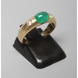AN EMERALD AND DIAMOND RING, the oval cabochon polished emerald tension set and flanked by two gypsy