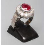 A RUBY AND DIAMOND CLUSTER RING, the circular facet cut ruby collet set to a border to twelve