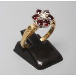 A GARNET AND DIAMOND CLUSTER RING, the central brilliant cut diamond with a border of six point