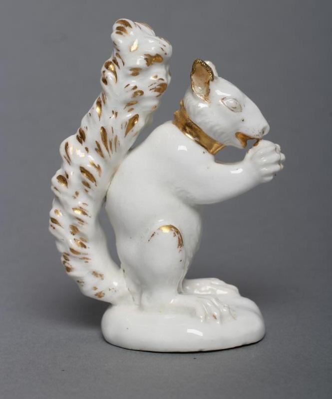 A DERBY PORCELAIN SQUIRREL, c.1800, modelled holding a nut to its mouth, with gilded highlights,