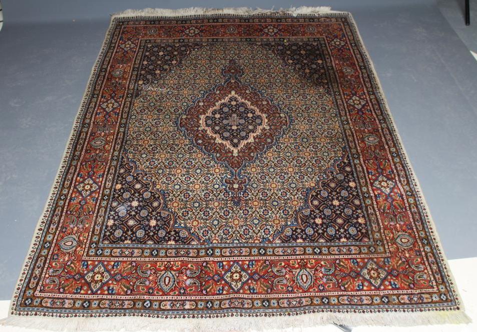 A PERSIAN RUG, the ivory floral field with central gul in red, ivory and navy blue, conforming