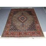 A PERSIAN RUG, the ivory floral field with central gul in red, ivory and navy blue, conforming