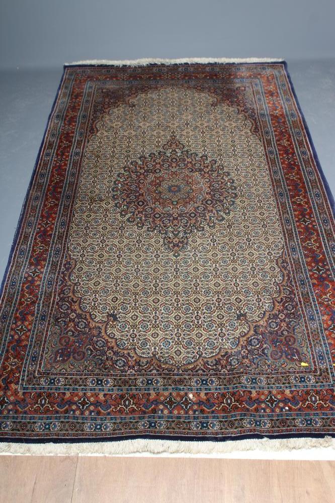 A PERSIAN RUG, the ivory field with all over repeating flowerhead and leaf pattern in shades of