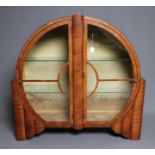 AN ART DECO WALNUT DISPLAY CABINET of circular form with two astragal glazed doors with turned brass