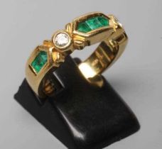 AN EMERALD AND DIAMOND HALF HOOP RING, the heavy cast panel centred by three channel cut emeralds