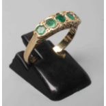 A FIVE STONE EMERALD HALF HOOP RING, the oval facet cut stones collet set to a plain 9ct gold shank,