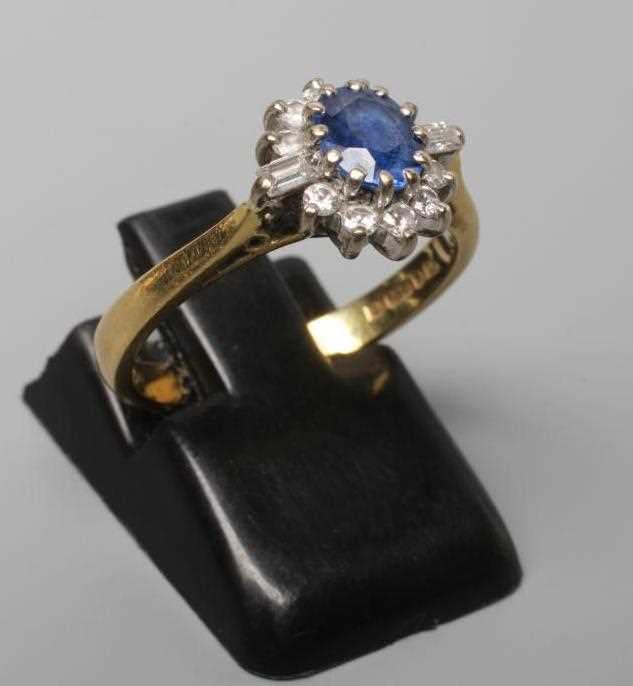 A SAPPHIRE AND DIAMOND CLUSTER RING, the oval facet cut sapphire claw set to a border of ten small