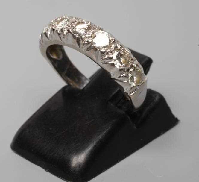 A SEVEN STONE DIAMOND HALF HOOP RING, the round brilliants line set to a plain white shank stamped