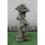 A CAST STONE FIGURE allegorical of Autumn, modelled as a Putto carrying a basket of fruit on his