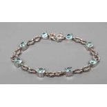 A BLUE TOPAZ BRACELET, the eight facet cut circular stones with pairs of 9ct white gold triangular