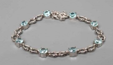 A BLUE TOPAZ BRACELET, the eight facet cut circular stones with pairs of 9ct white gold triangular