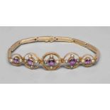 AN EDWARDIAN AMETHYST AND SEED PEARL BRACELET, the five graduated open circlets each centred by a
