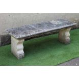 A CAST STONE BENCH, the moulded edged oblong seat raised on flower moulded square section end