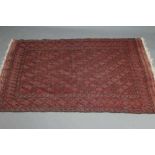 A PERSIAN TRIBAL RUG, the soft red ground with trellis patterned field in shades of grey, within a