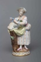 A MEISSEN PORCELAIN FIGURE, late 19th century, modelled as a shepherdess wearing a blue hat, lace