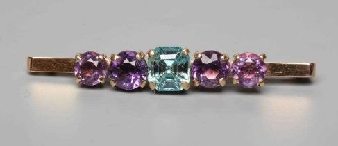 AN EDWARDIAN BROOCH centred by a cushion cut blue zircon flanked by two pairs of graduated amethysts