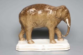 A STAFFORDSHIRE POTTERY MODEL OF JUMBO, the elephant standing on a gilt lined shaped oblong base, 11